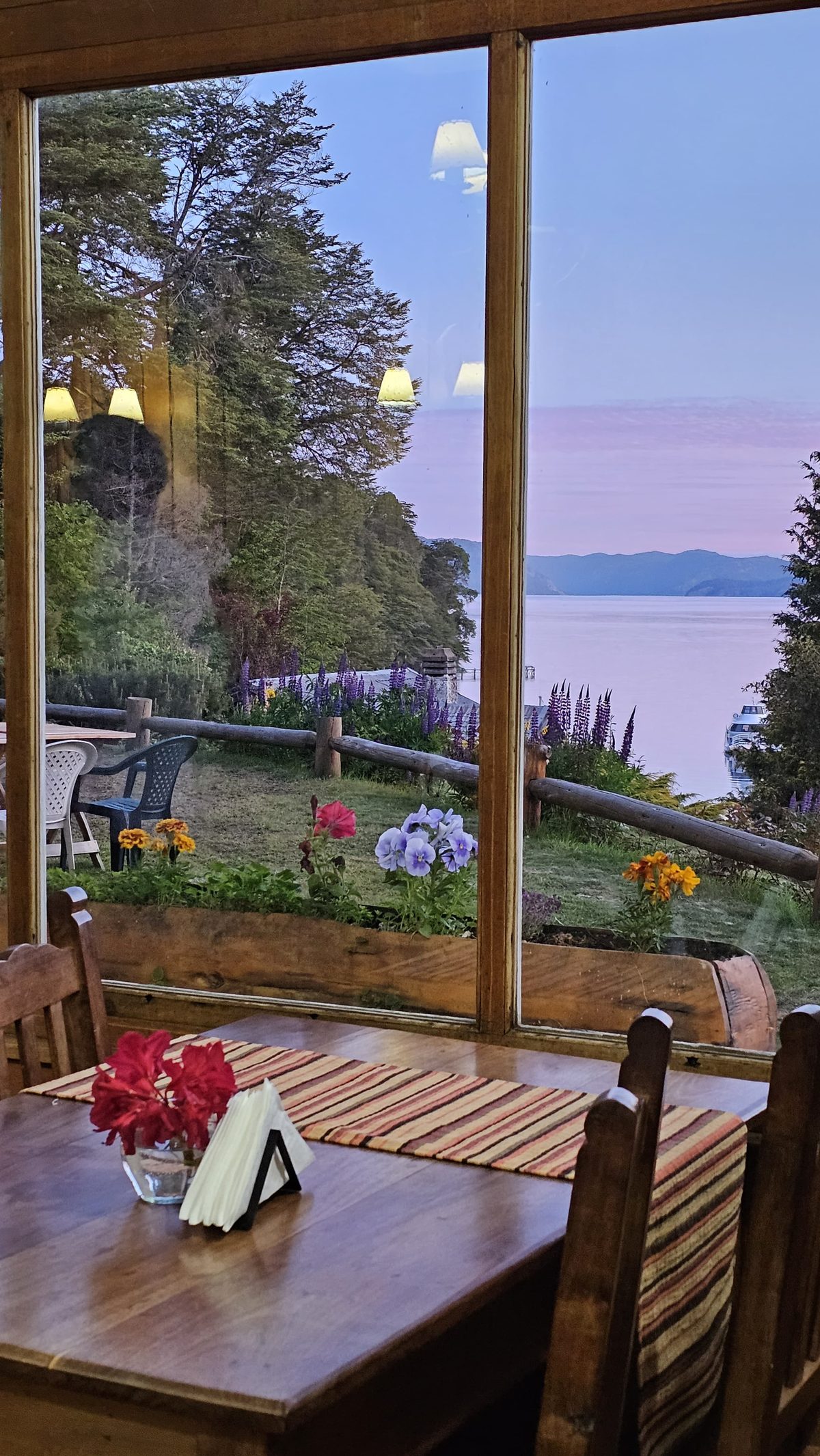 Mesa junto al ventanal del comedor, con el lago al atardecer